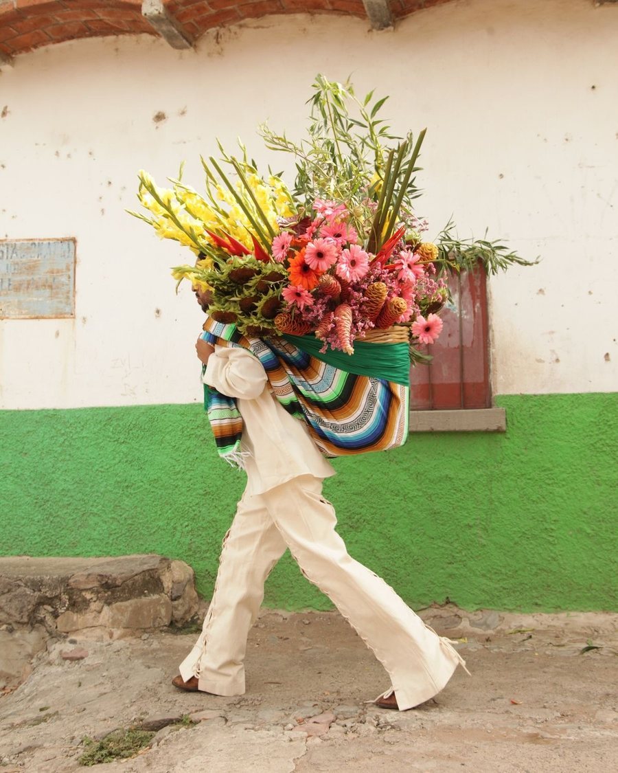 Hombre caminando con una canasta enorme de flores