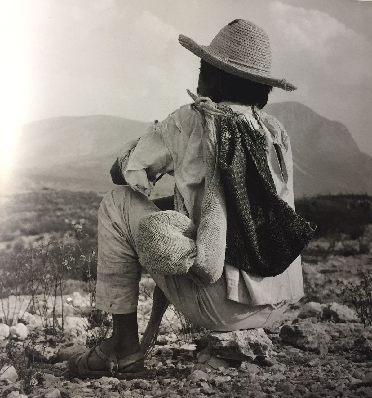 Un hombre con sombrero de ala ancha y morral, de espaldas, mirando el valle