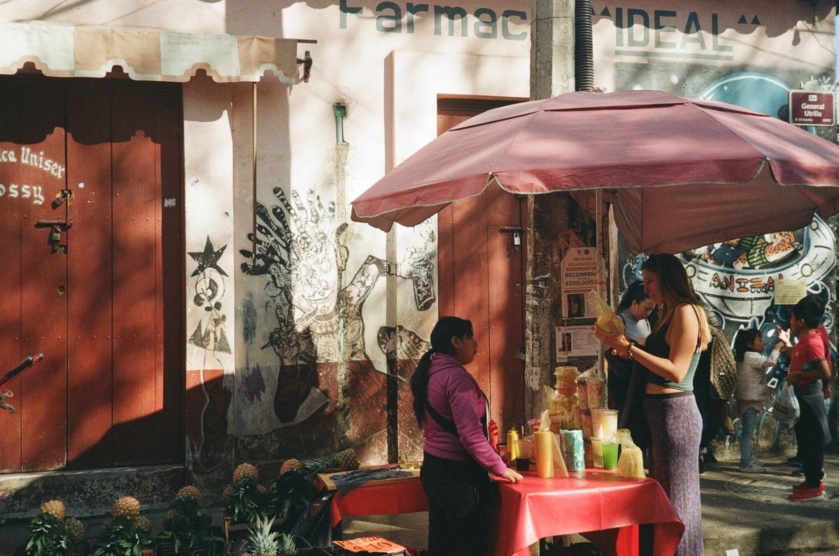Un puesto de mercado bajo una sombrilla en una calle de colores