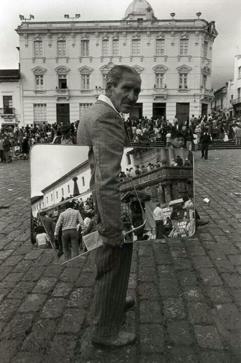 Un hombre de saco parado en una plaza, en blanco y negro